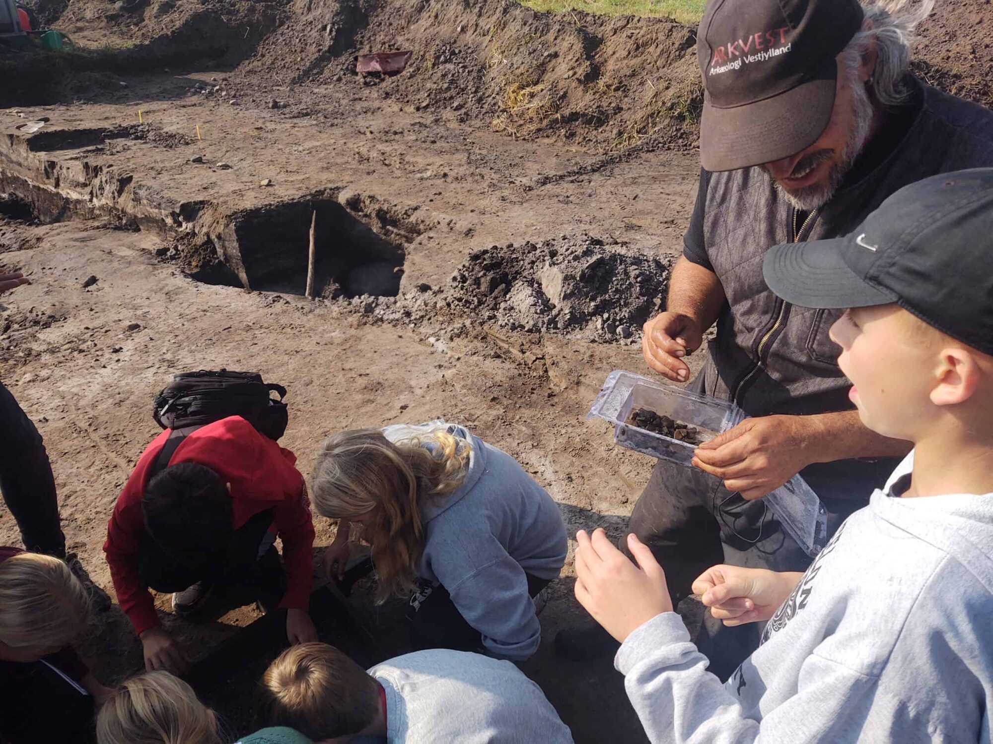 A group of people gathered around a hole, possibly engaged in a discussion or observing something.