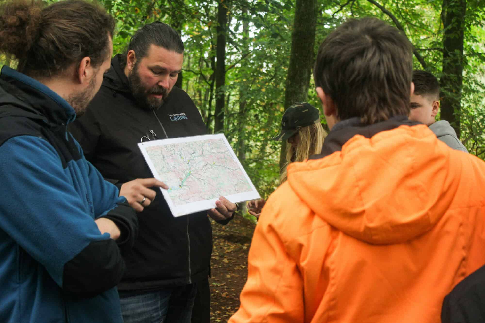 1. A group of people standing in the woods, examining a map together.